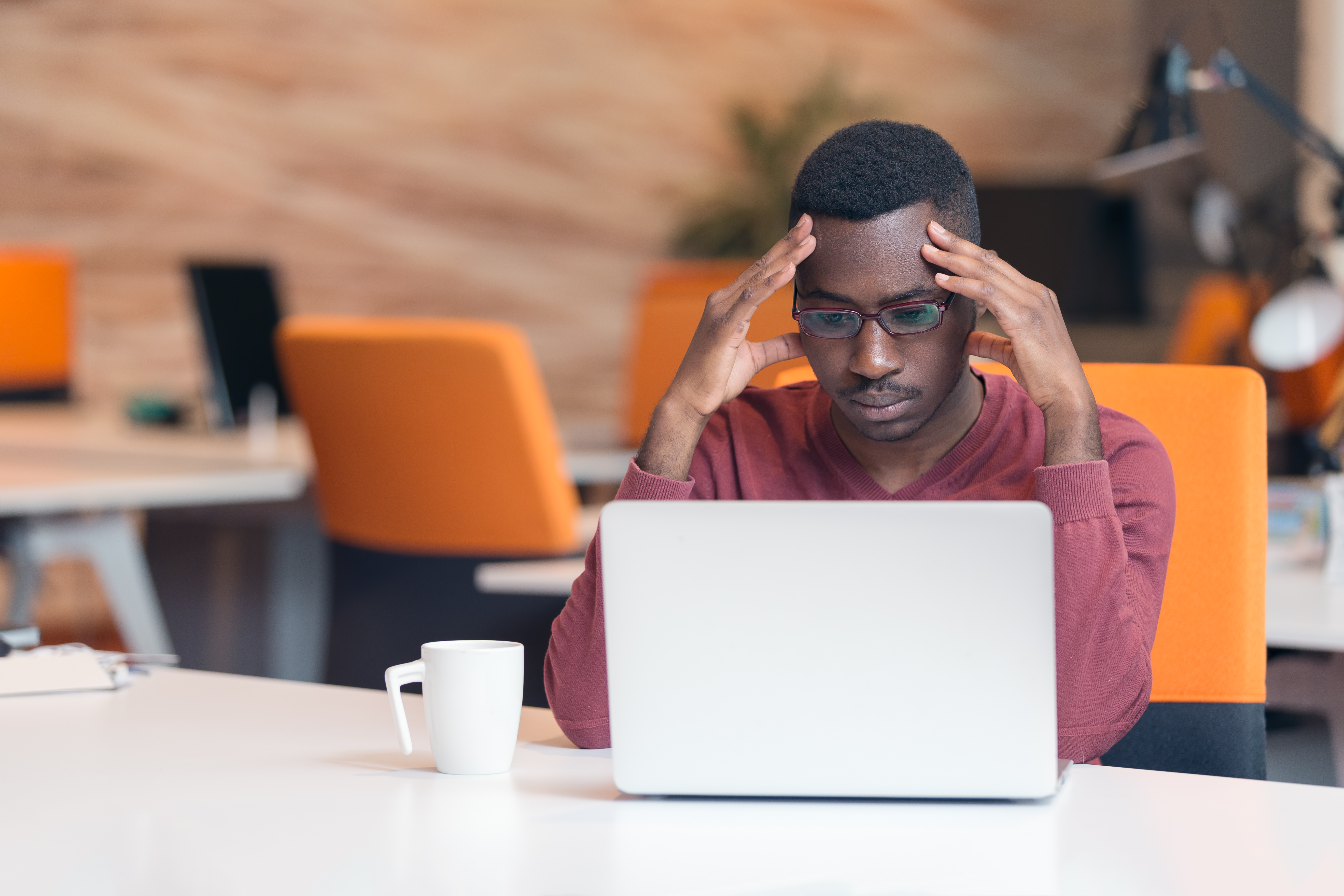 Handsome successful African American looking at the screen with serious face expression at modern startup office